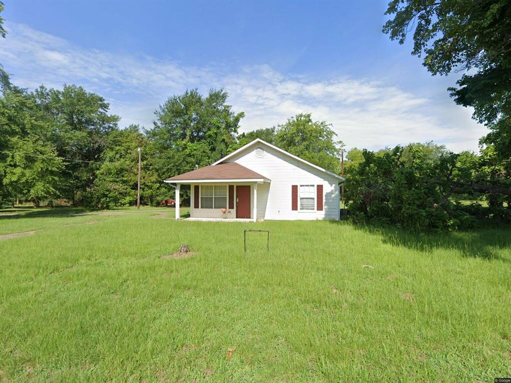 414 Tobe Street Gilmer, TX 75644 - Photo 1 of 9 White exterior siding with a red front door, covered porch, and red window shutters