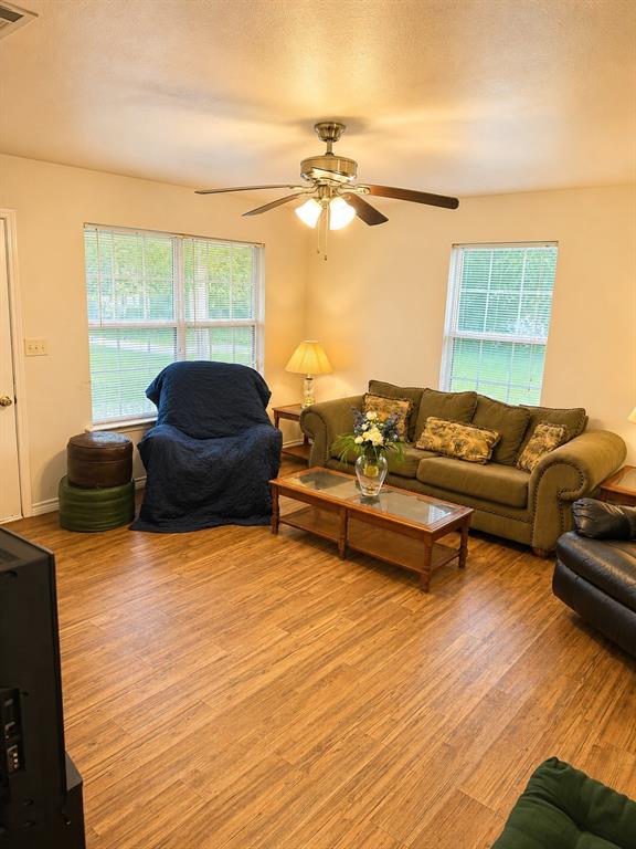 414 Tobe Street Gilmer, TX 75644 - Photo 2 of 9 Spacious living area featuring wood-finish flooring, light-toned walls, and multiple windows