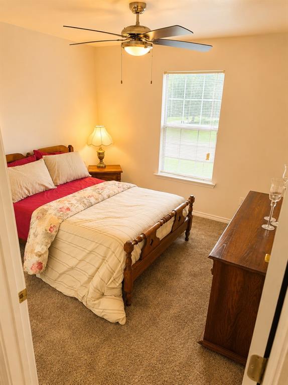 414 Tobe Street Gilmer, TX 75644 - Photo 8 of 9 Carpeted room featuring a ceiling fan with light fixture, a single window, and a wood-finish dresser