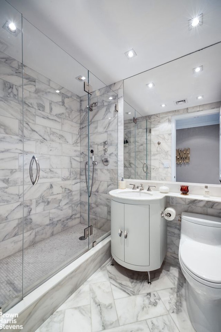 15 West 63rd Street, Unit 20B Manhattan, NY 10023 - Photo 11 of 14 a large white bathroom with a sink a toilet and shower