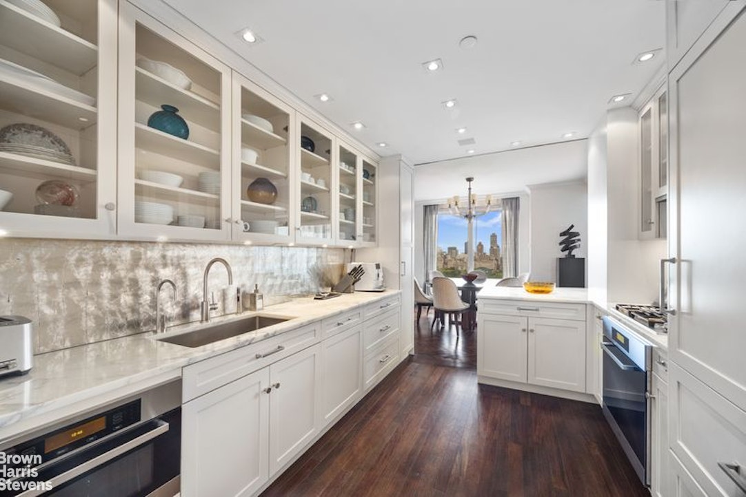 15 West 63rd Street, Unit 20B Manhattan, NY 10023 - Photo 6 of 14 a large white kitchen with a large window a sink and stainless steel appliances