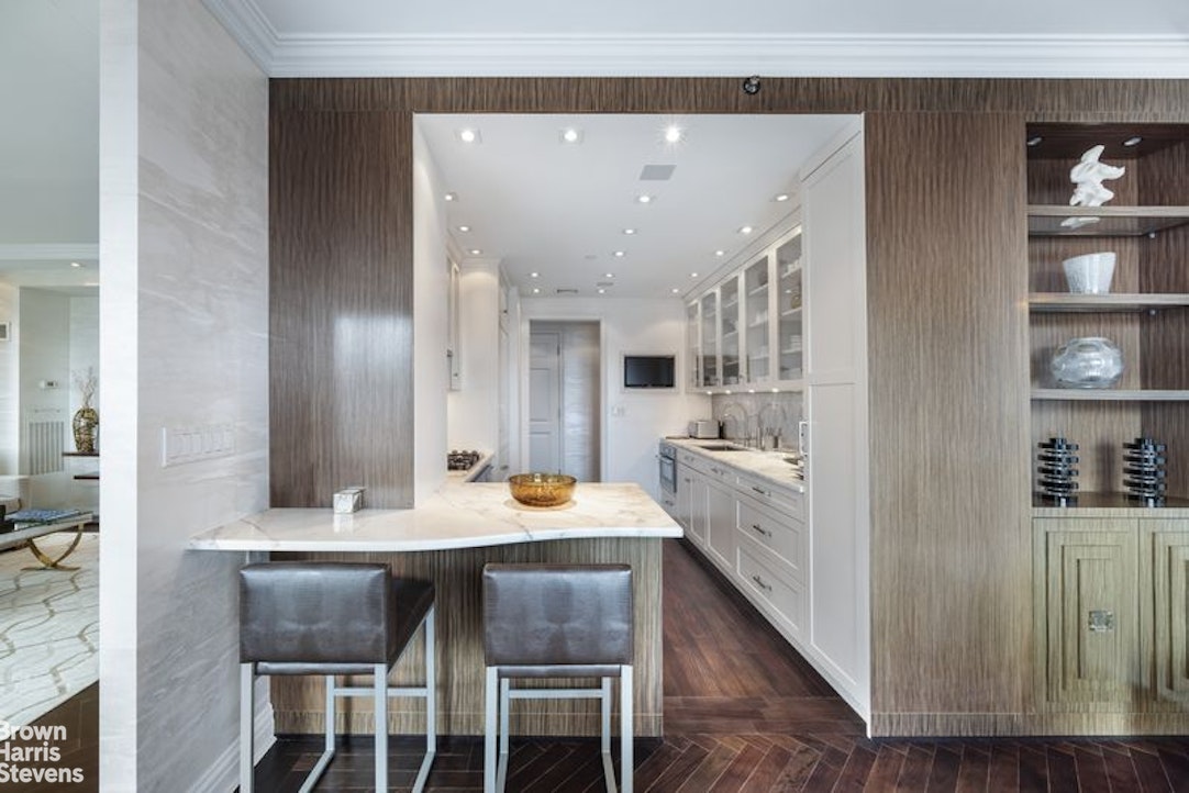 15 West 63rd Street, Unit 20B Manhattan, NY 10023 - Photo 7 of 14 a large white kitchen with granite countertop a table chairs sink and cabinets
