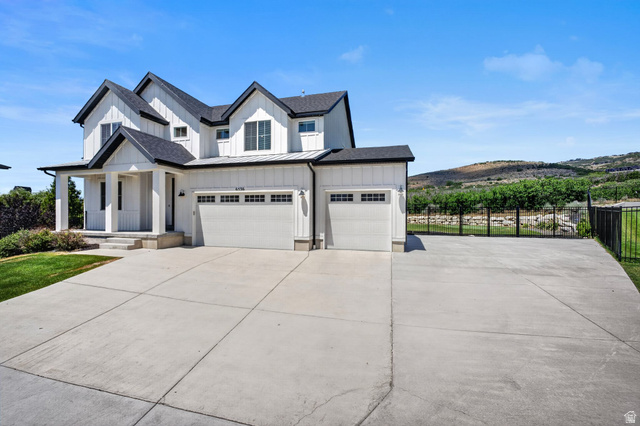 6536 West Muirfield Road Highland, UT 84003 - Photo 43 of 48 Modern farmhouse exterior featuring white board and batten siding, a prominent covered porch, and a multi-car concrete driveway