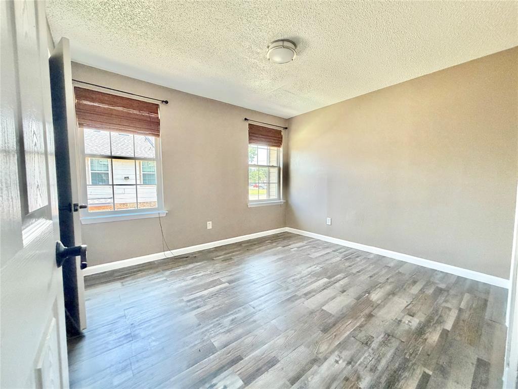 8001 Rothington Road, Unit 33 Dallas, TX 75227 - Photo 12 of 15 Room featuring wood-finish flooring, two windows with blinds, neutral wall paint, and a ceiling-mounted light fixture