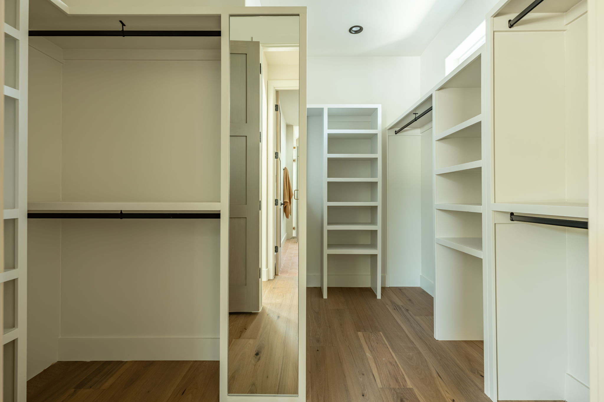 4713 Bolm Road Austin, TX 78702 - Photo 27 of 40 Walk-in closet featuring wood-finish flooring, built-in shelving, integrated hanging rods, and an expansive full-length mirror