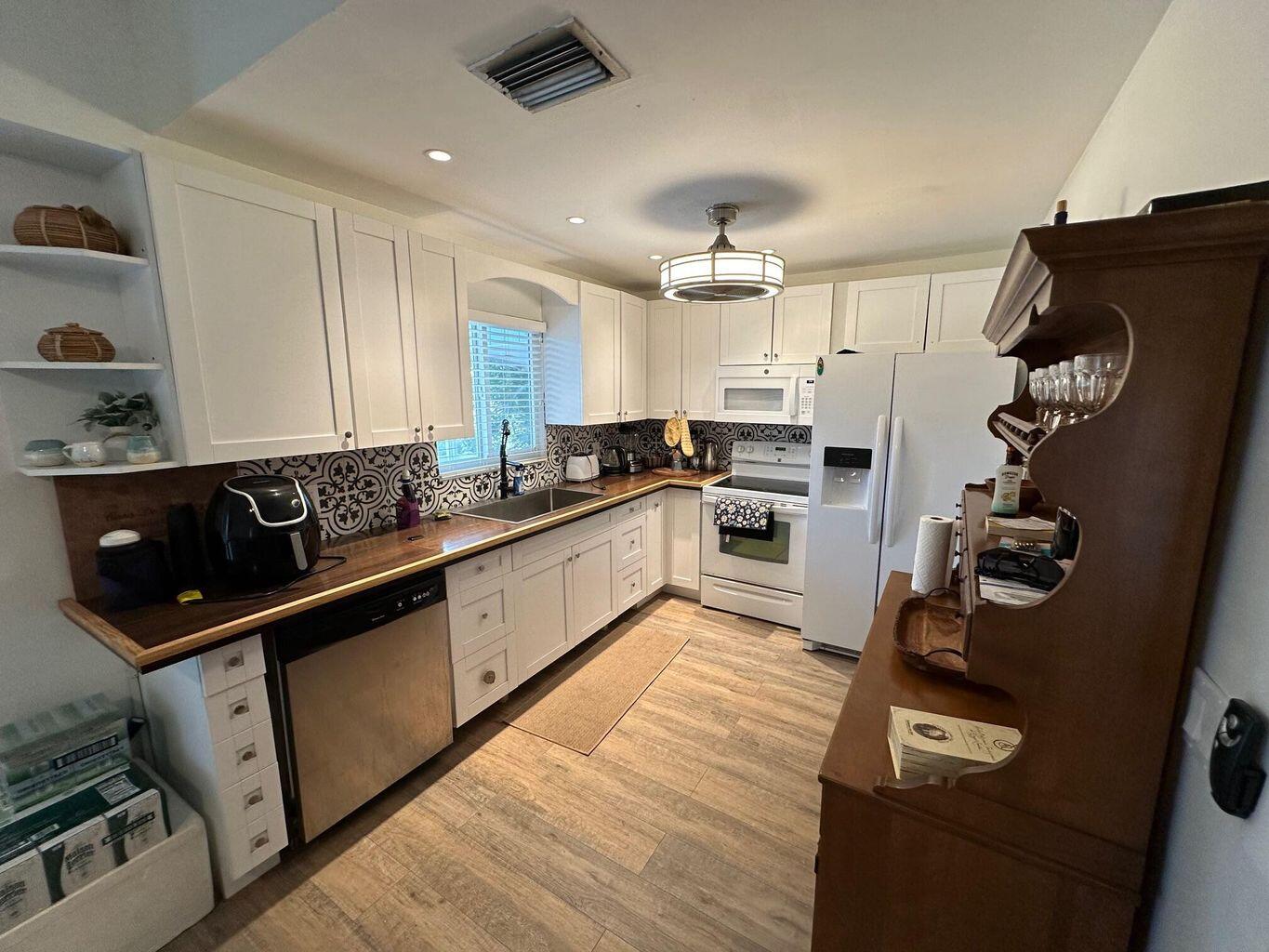 3 Meridian Avenue Key Largo, FL 33037 - Photo 6 of 18 a kitchen with granite countertop a refrigerator a sink and white cabinets