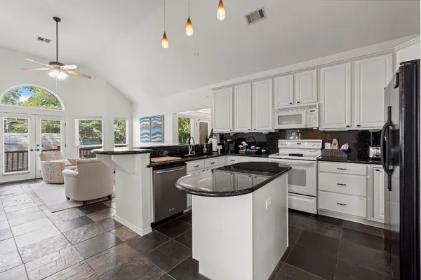 a kitchen with a white stove top oven a sink a dining table and chairs