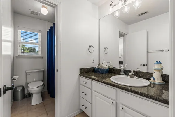 a bathroom with a granite countertop sink a toilet and a mirror