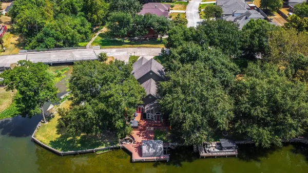 an aerial view of a house with a yard lake house and trees in the background