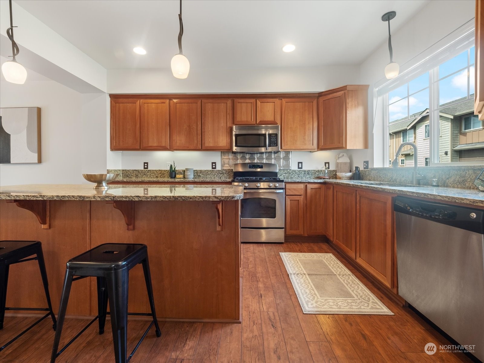 4625 Northeast 3rd Lane, Unit G3 Renton, WA 98059 - Photo 9 of 40 a kitchen with stainless steel appliances granite countertop wooden cabinets a sink a stove a refrigerator and island with wooden floor