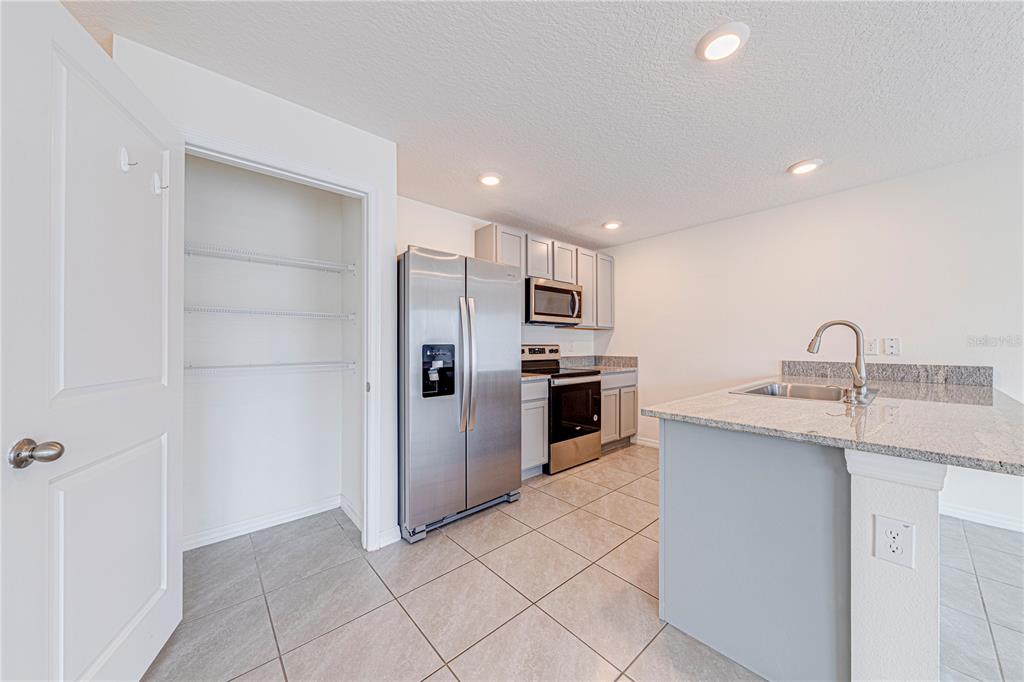 34026 Soaring Bamboo Path Wesley Chapel, FL 33543 - Photo 8 of 34 a kitchen with stainless steel appliances granite countertop a sink a stove a refrigerator and island
