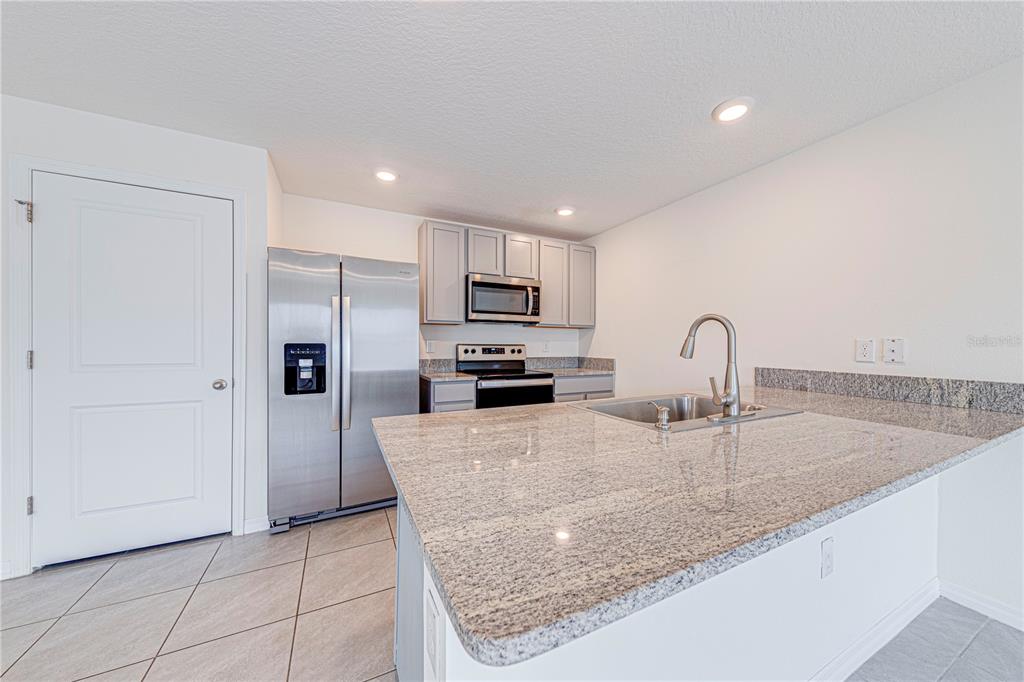 34026 Soaring Bamboo Path Wesley Chapel, FL 33543 - Photo 10 of 34 a kitchen with stainless steel appliances granite countertop a sink a stove and a refrigerator
