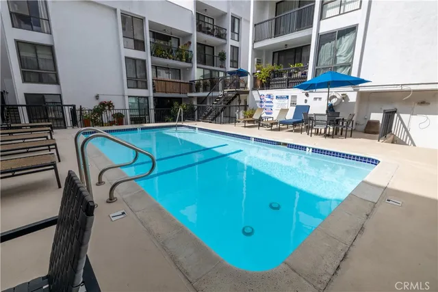 a view of a swimming pool with a chairs and table in the patio
