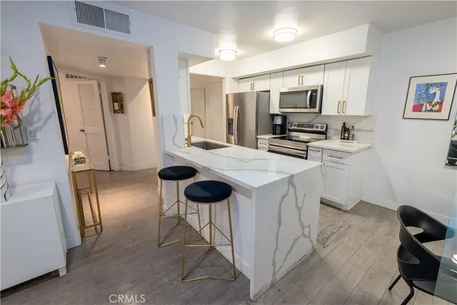 a kitchen with stainless steel appliances a stove a refrigerator a sink dishwasher and wooden cabinets with wooden floor