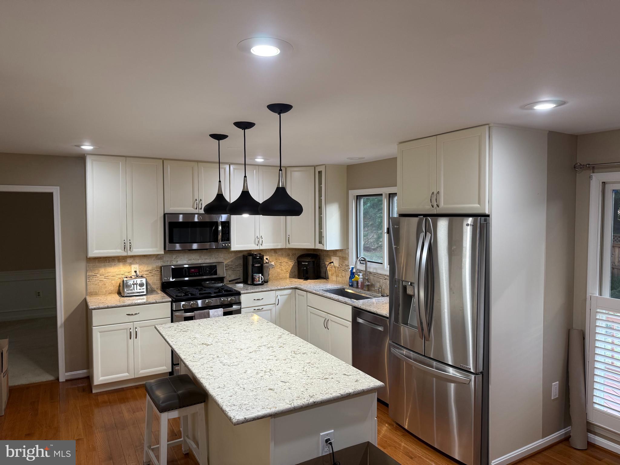 3869 Appaloosa Drive Woodbridge, VA 22192 - Photo 8 of 16 a kitchen with stainless steel appliances a refrigerator a sink a stove a microwave and wooden floor