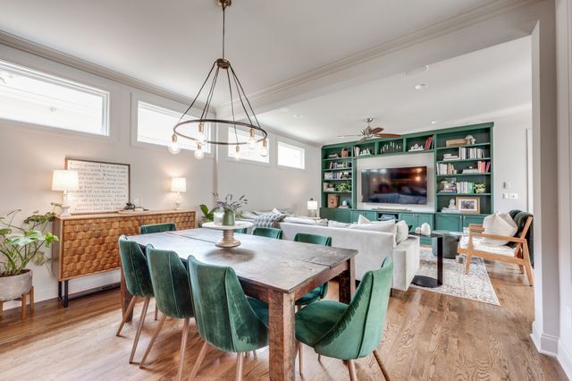 a kitchen with stainless steel appliances granite countertop a kitchen island a stove a refrigerator and a dining table with wooden floor