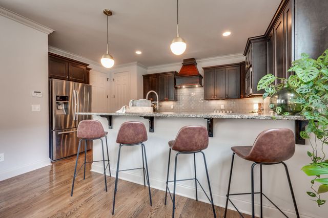 a large kitchen with stainless steel appliances granite countertop a stove top oven a sink dishwasher a dining table and chairs with wooden floor
