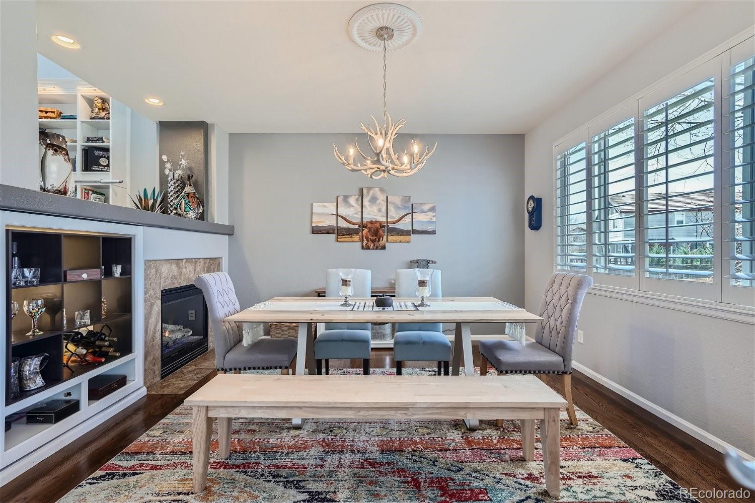 3085 Meadowbrook Place Dacono, CO 80514 - Photo 14 of 32 a living room with furniture a fireplace and a chandelier