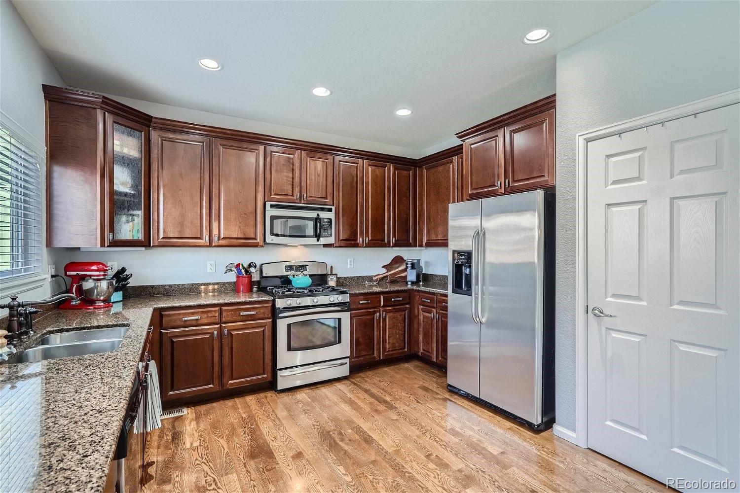 3085 Meadowbrook Place Dacono, CO 80514 - Photo 7 of 32 a kitchen with stainless steel appliances granite countertop a refrigerator sink and cabinets