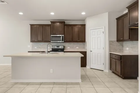 a kitchen with kitchen island granite countertop a stove top oven a sink and a refrigerator