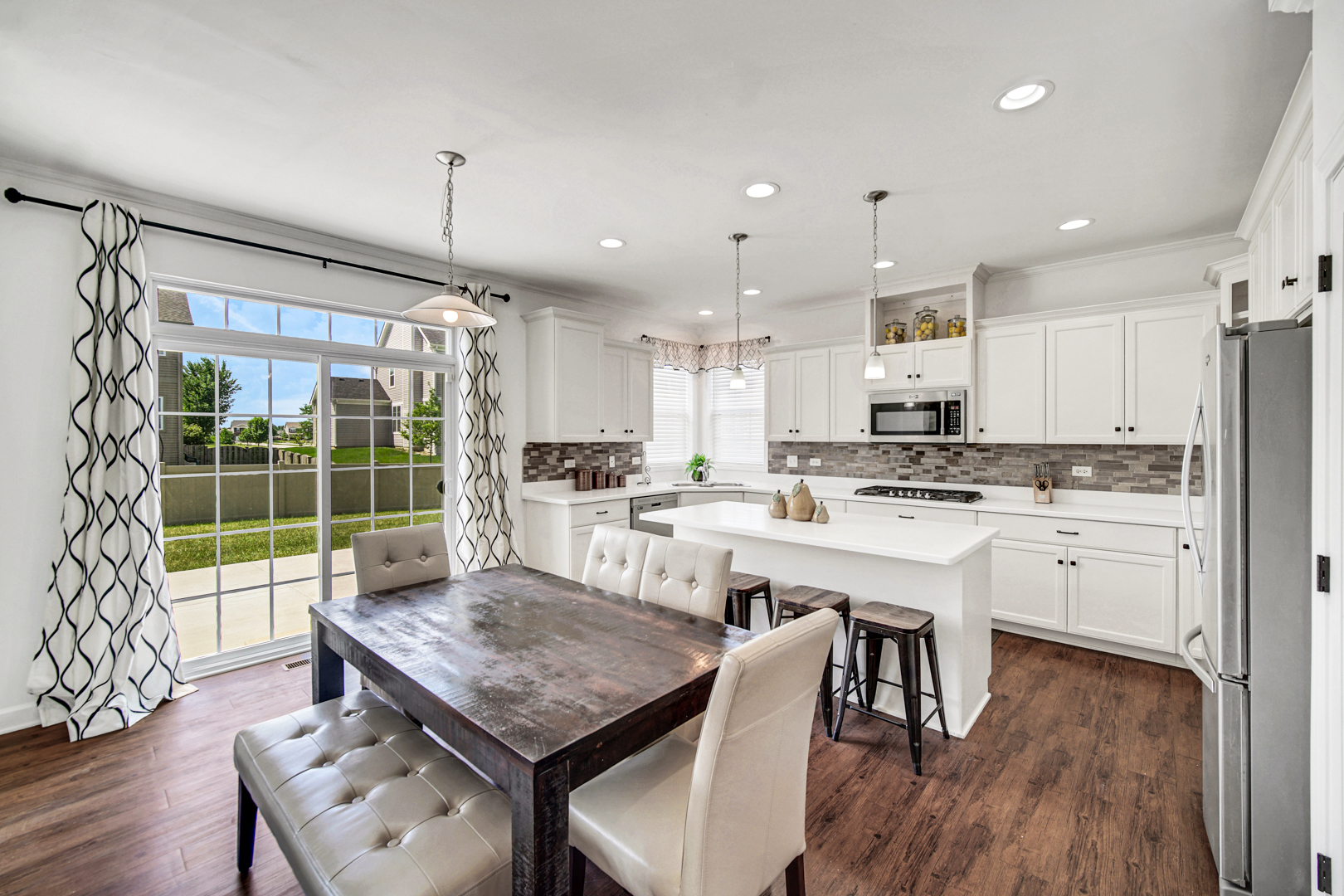 16512 Mueller Circle Plainfield, IL 60586 - Photo 7 of 29 a kitchen with a table chairs refrigerator and wooden floor