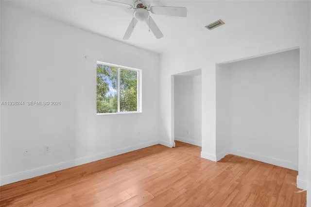a view of empty room with wooden floor and fan