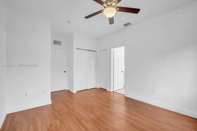 an empty room with wooden floor and a ceiling fan