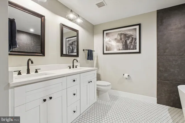 a bathroom with a toilet sink double vanity and mirror