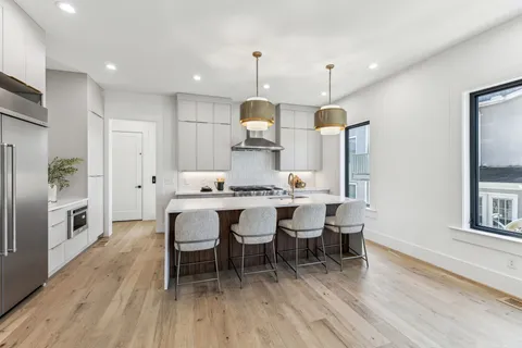 a kitchen with stainless steel appliances kitchen island a table and chairs in it