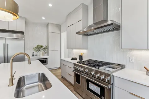 a kitchen with stainless steel appliances granite countertop a stove a sink dishwasher a refrigerator and a wooden floor