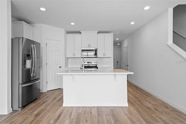a kitchen with stainless steel appliances granite countertop a refrigerator a stove and a microwave with wooden floor