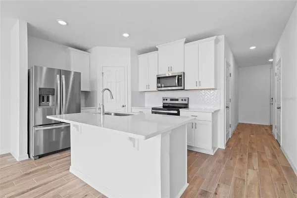 a kitchen with stainless steel appliances a sink stove refrigerator and cabinets