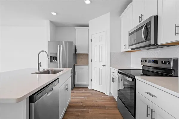 a kitchen with stainless steel appliances granite countertop a sink stove microwave and refrigerator