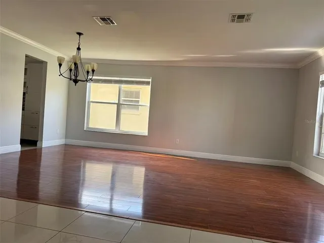 a view of an empty room with window and wooden floor