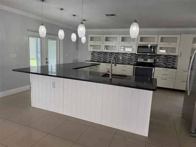 a large kitchen with granite countertop a sink and a stove