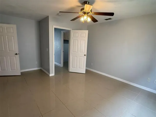 an empty room with closet and a chandelier fan