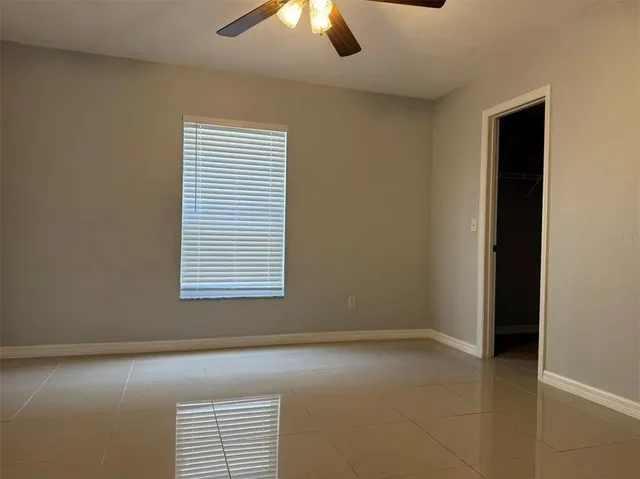 an empty room with a window and chandelier fan