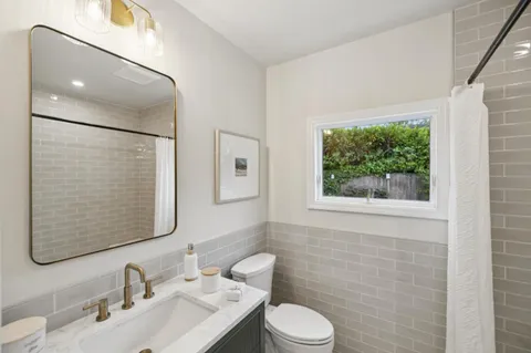 a bathroom with a toilet a sink a mirror and a window