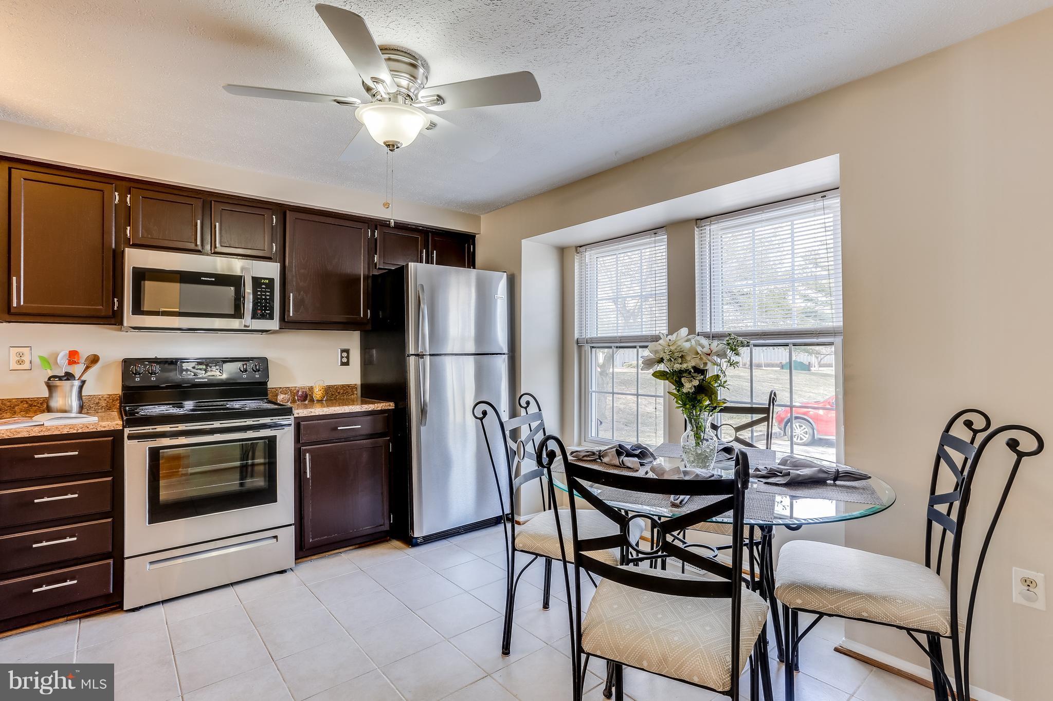 7204 Procopio Circle Columbia, MD 21046 - Photo 3 of 30 a kitchen with stainless steel appliances granite countertop a stove a refrigerator a microwave oven with a dining table and chairs
