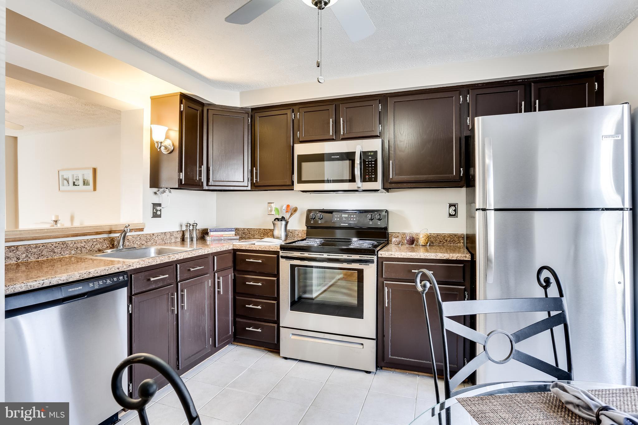 7204 Procopio Circle Columbia, MD 21046 - Photo 4 of 30 a kitchen with stainless steel appliances granite countertop a stove a sink dishwasher a refrigerator and a microwave with wooden floor