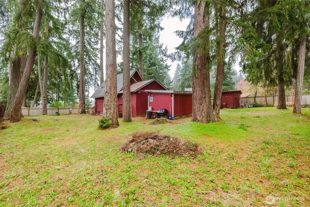 a view of a backyard with large trees and barn