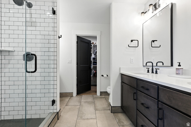 6039 North Westridge Road Heber City, UT 84032 - Photo 17 of 22 Contemporary bathroom featuring a spacious walk-in shower with white subway tile, a dual vanity with dark wood cabinetry and white countertops, large format tile flooring, and matte black fixtures throughout