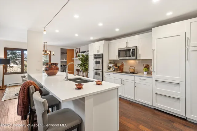 a open kitchen with stainless steel appliances kitchen island granite countertop a stove and white cabinets