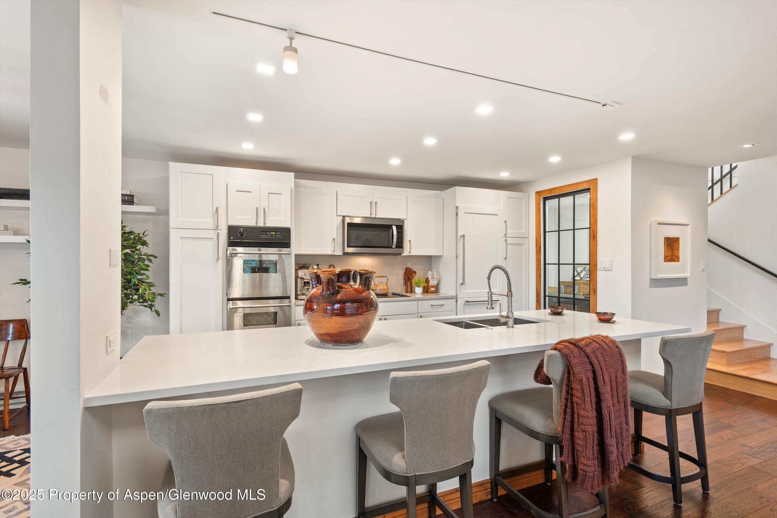 382 Meadow Ranch Road, Unit F4B Snowmass Village, CO 81615 - Photo 6 of 30 a kitchen with stainless steel appliances granite countertop a table chairs refrigerator and microwave