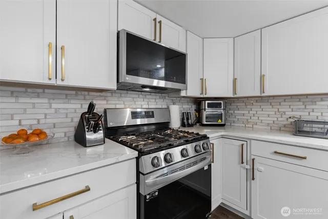 a kitchen with stainless steel appliances white cabinets and a stove a oven with wooden floor