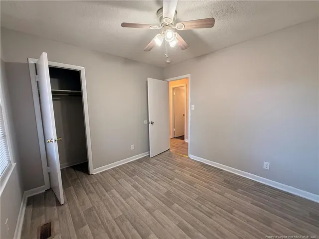 an empty room with wooden floor and a ceiling fan
