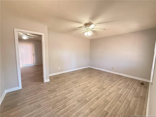 an empty room with wooden floor and fan