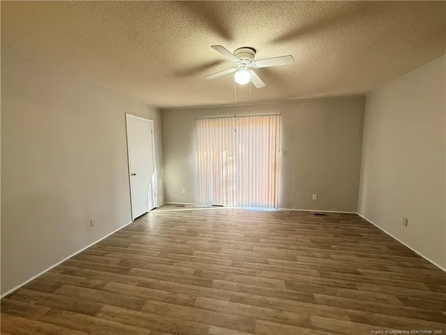 a view of an empty room with window and chandelier fan