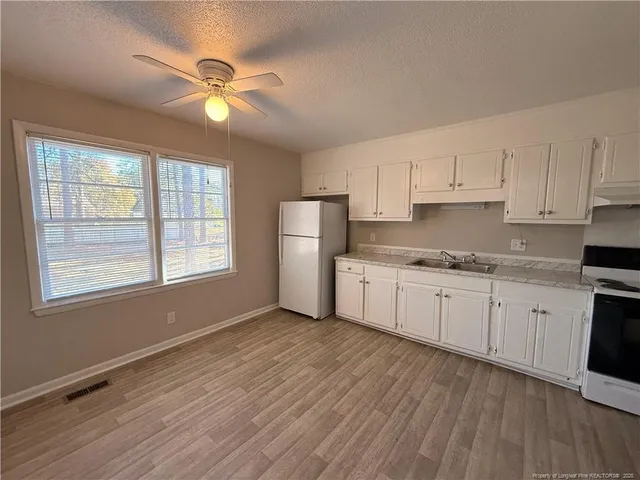 a kitchen with granite countertop white cabinets and white appliances