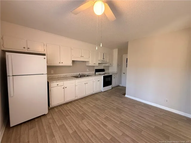 a kitchen with granite countertop white cabinets and white appliances